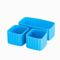 A set of three blue silicone bento cups of different sizes, with one rectangular and two square cups.