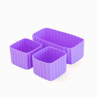 A set of three purple silicone bento cups of different sizes, with one rectangular and two square cups.